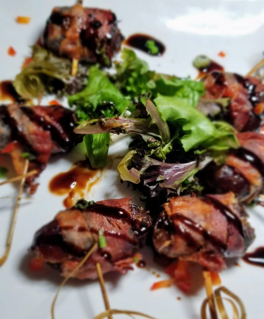 Bacon-wrapped Stuffed Dates stuffed with feta cheese and drizzled with fig balsamic reduction